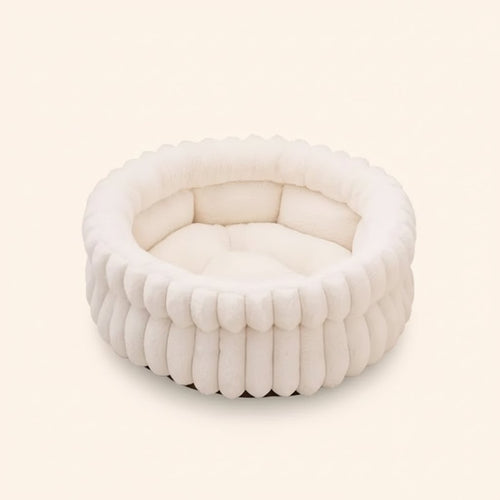 Cama redonda CalmNest branca, com rebordo, sobre fundo claro